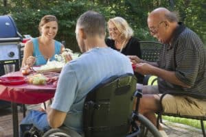 Man with spinal cord injury in wheelchair at family outdoor